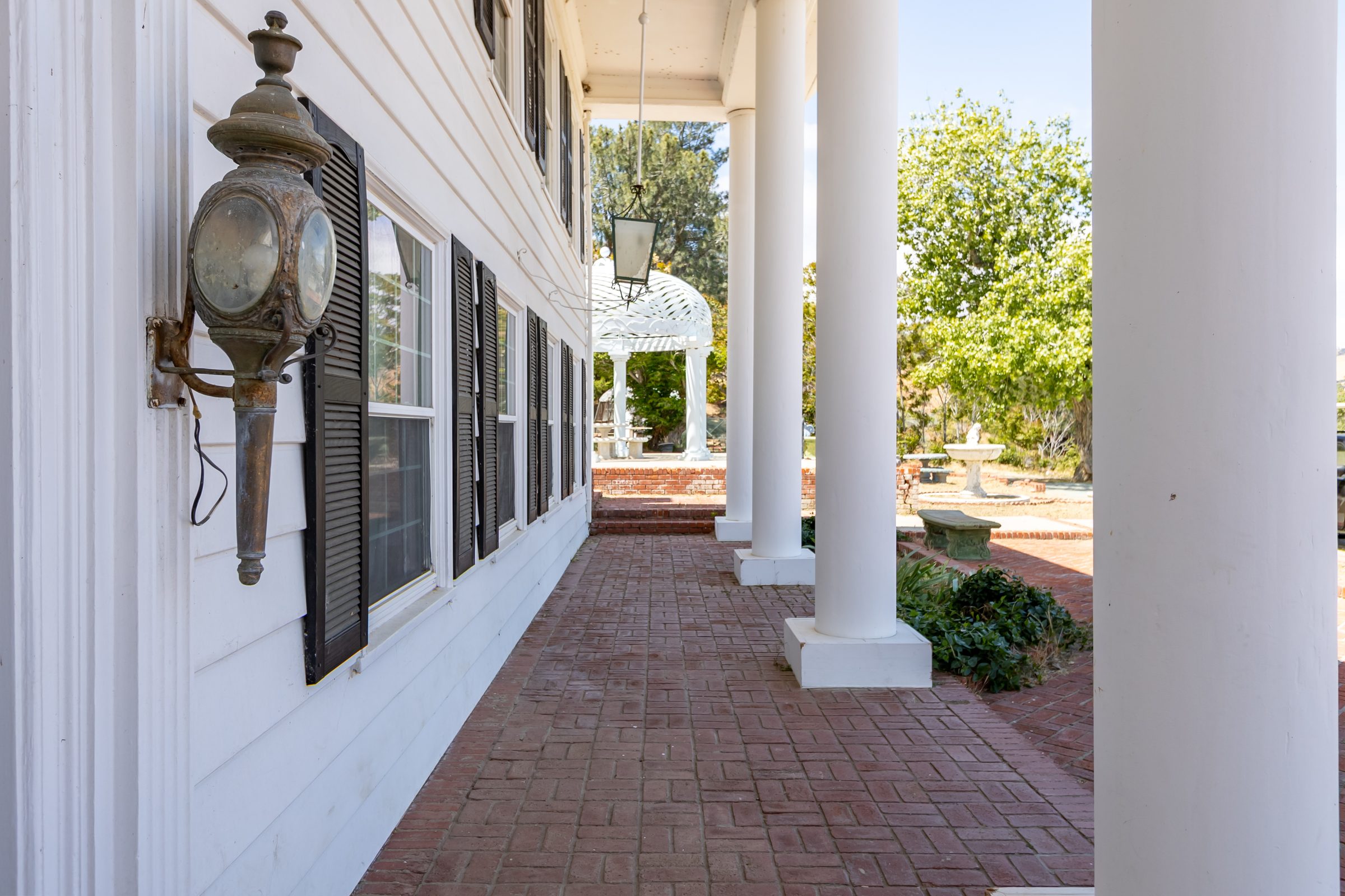 Brick porch with white columns and a carriage lamp