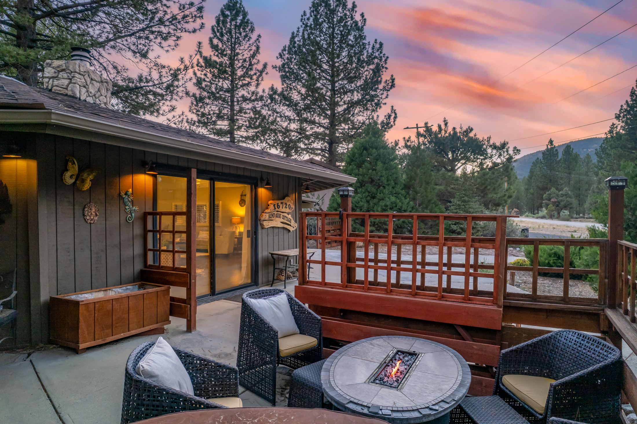 Twilight patio with a lit fire pit and wicker chairs at a mountain cabin