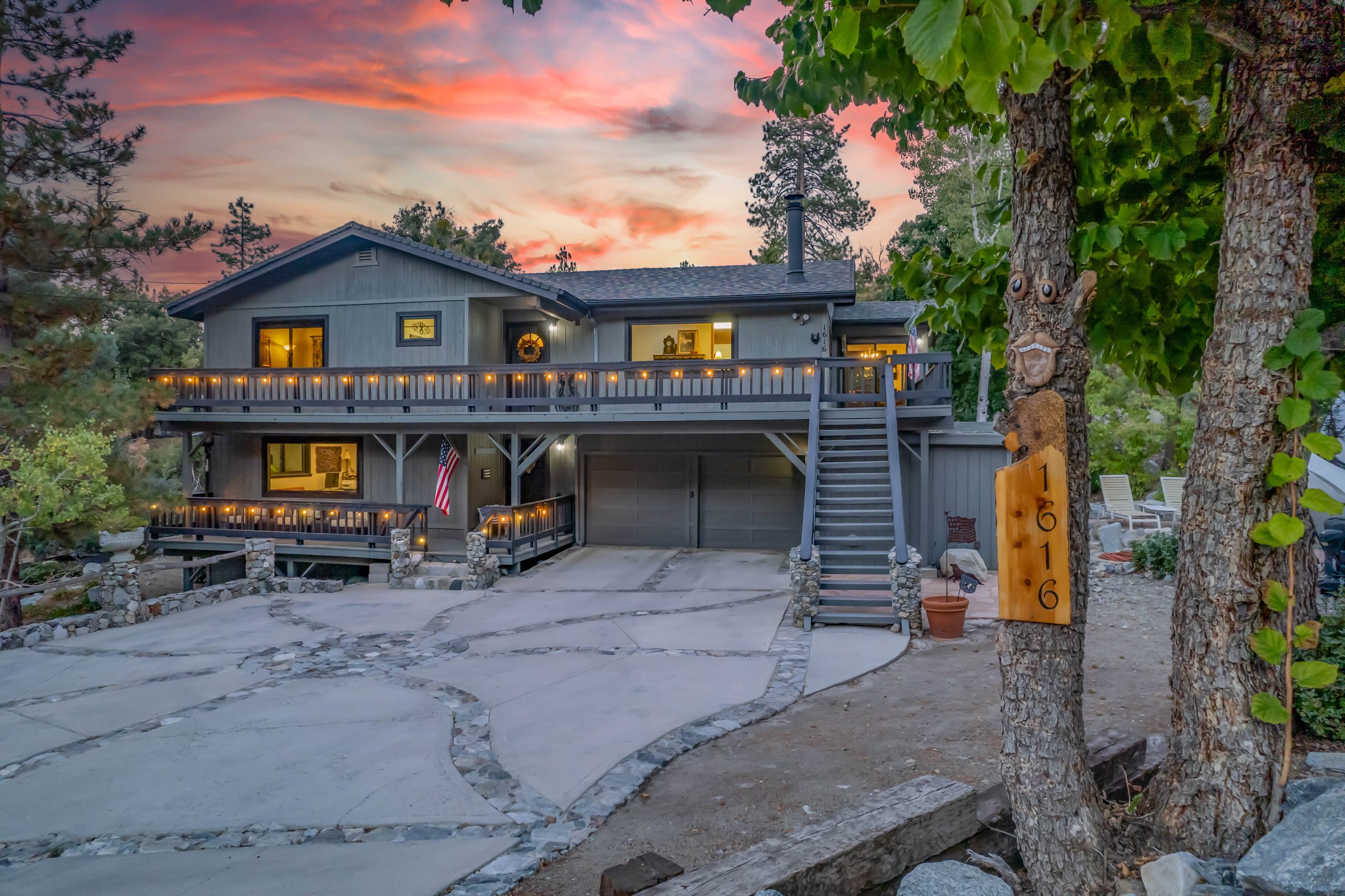 Front of a two-story mountain home at twilight, deck lights glowing